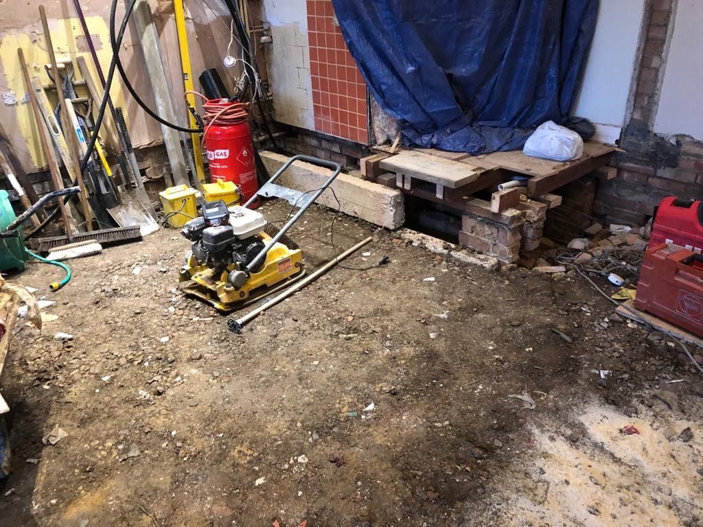 A yellow machine is sitting on the ground in a messy room.