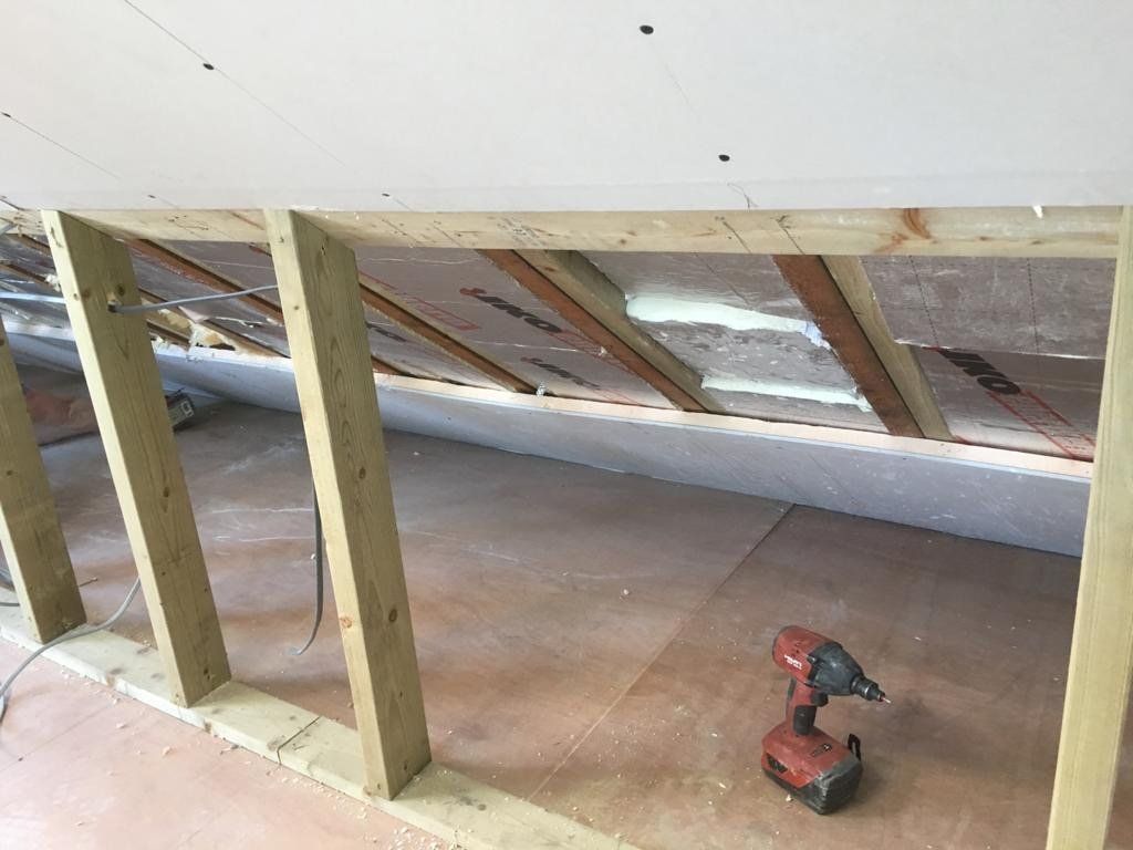 A drill is sitting on the floor in a room under construction.