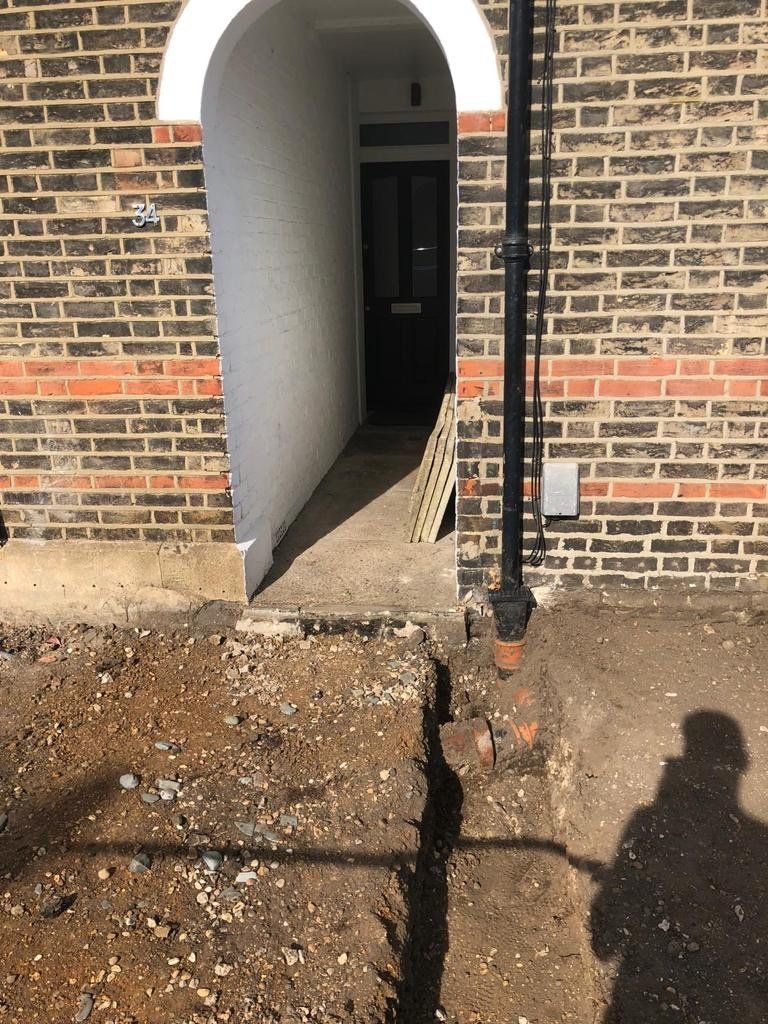 A brick building with a hole in the ground in front of it
