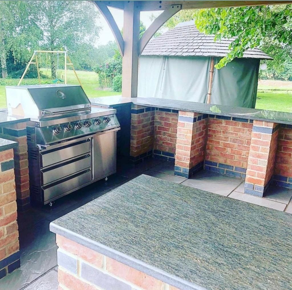 An outdoor kitchen with a grill and a brick wall
