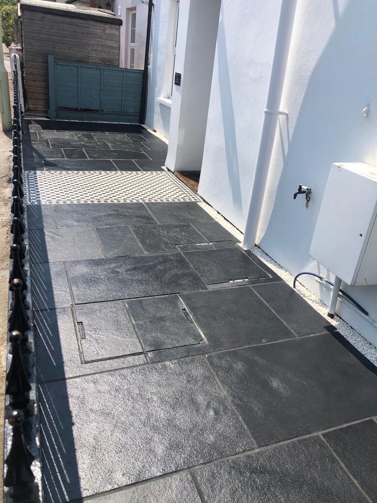 A black tiled walkway leading to a white building.