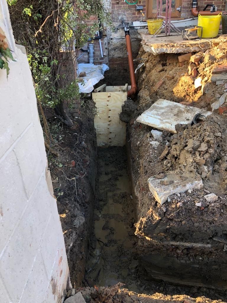 A large hole in the ground next to a brick wall.