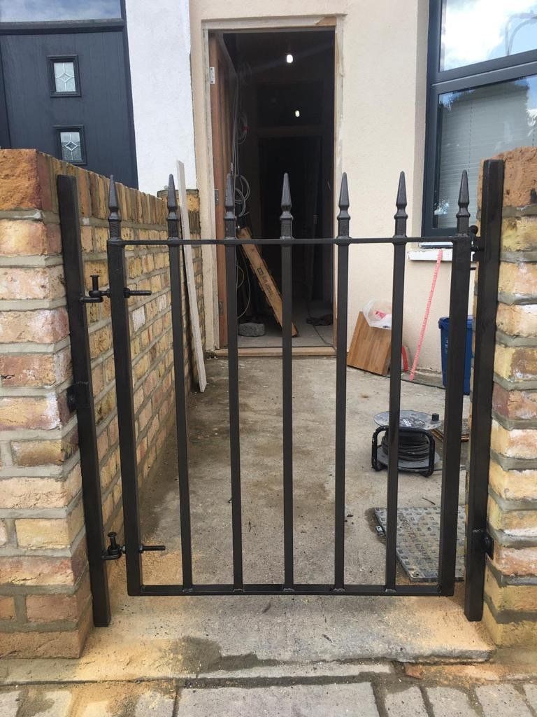 A wrought iron gate is sitting in front of a brick wall.