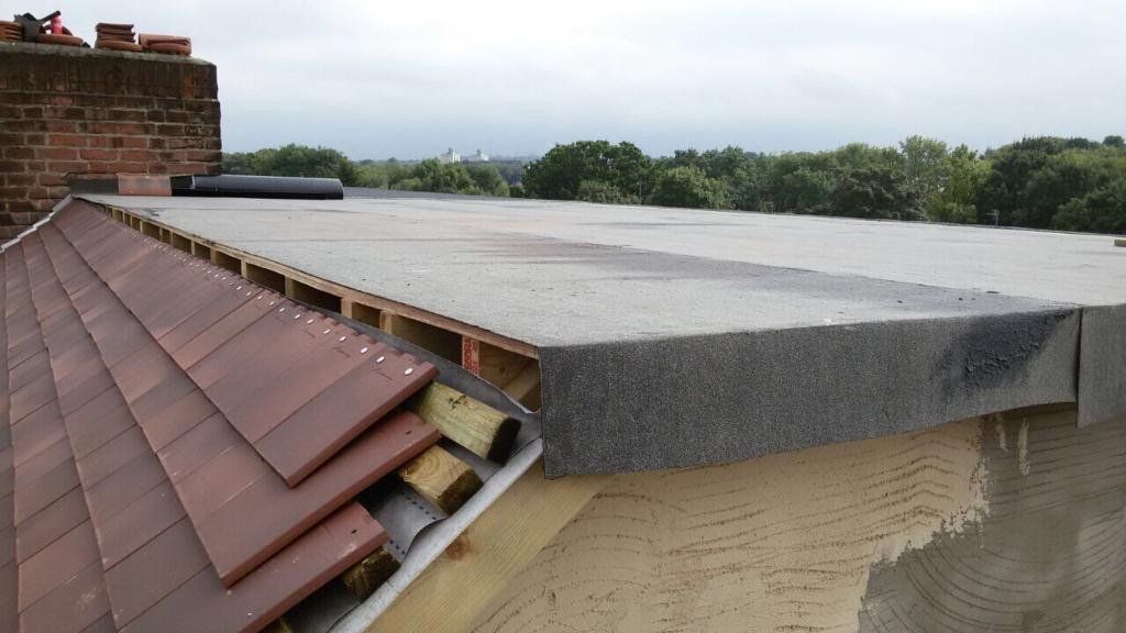 A roof with a lot of tiles on it and a chimney in the background.
