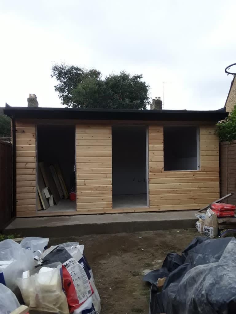 A wooden shed is being built in a backyard.