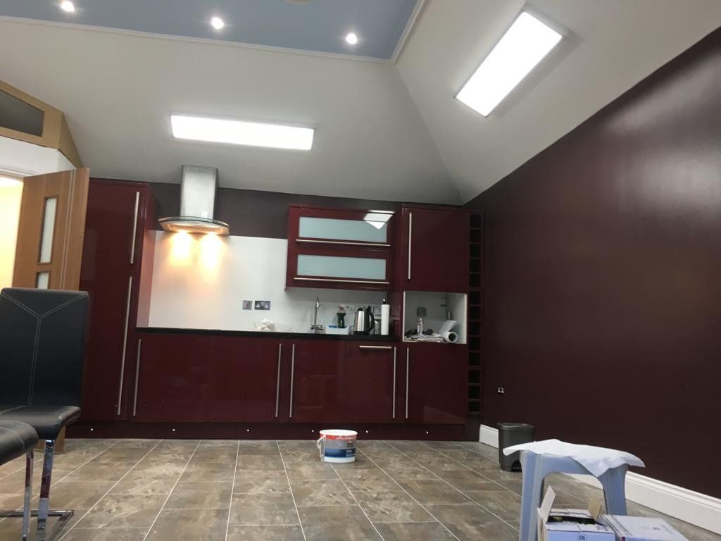A kitchen is being painted in burgundy and white.