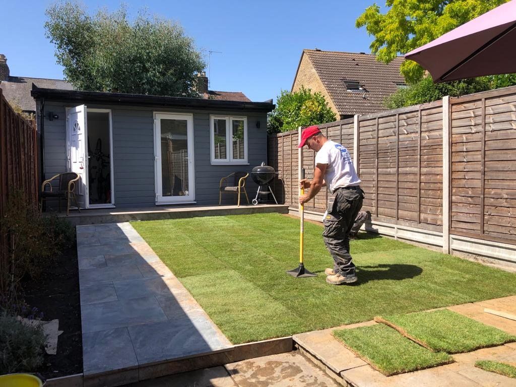A man is working on a lawn in a backyard.