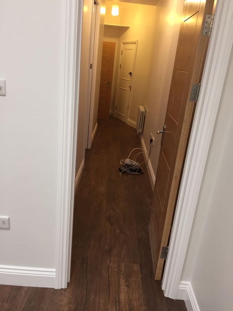 A long hallway with wooden floors and white walls.