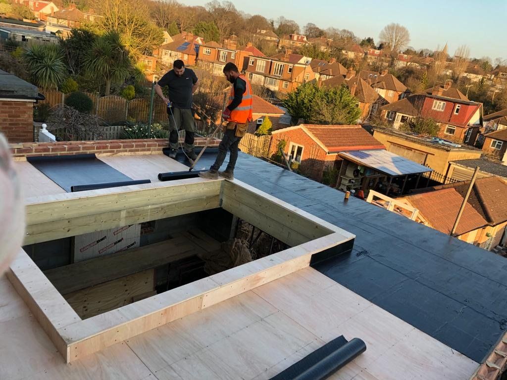 Two men are working on the roof of a house.