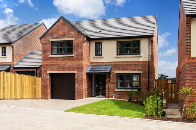 A brick house with a garage and a wooden fence in front of it.
