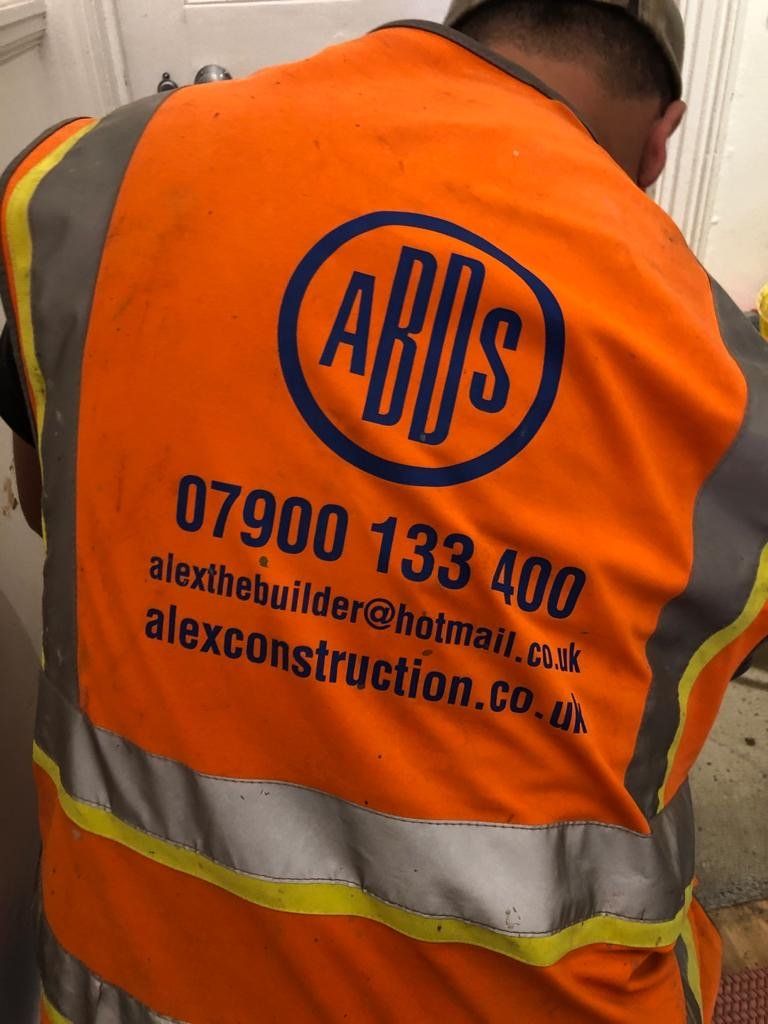 A man wearing an orange vest that says alex construction on it