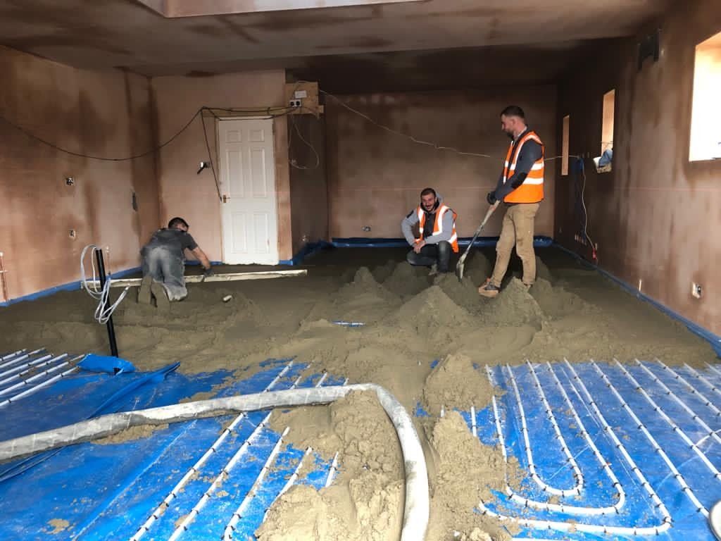 A group of men are working on a concrete floor in a room.