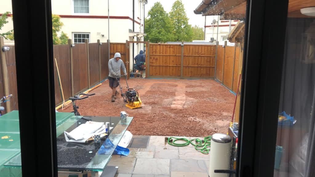 A group of people are working on a patio in a backyard.