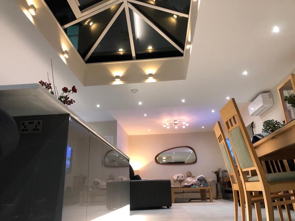 A living room with a couch , table , chairs and a skylight.