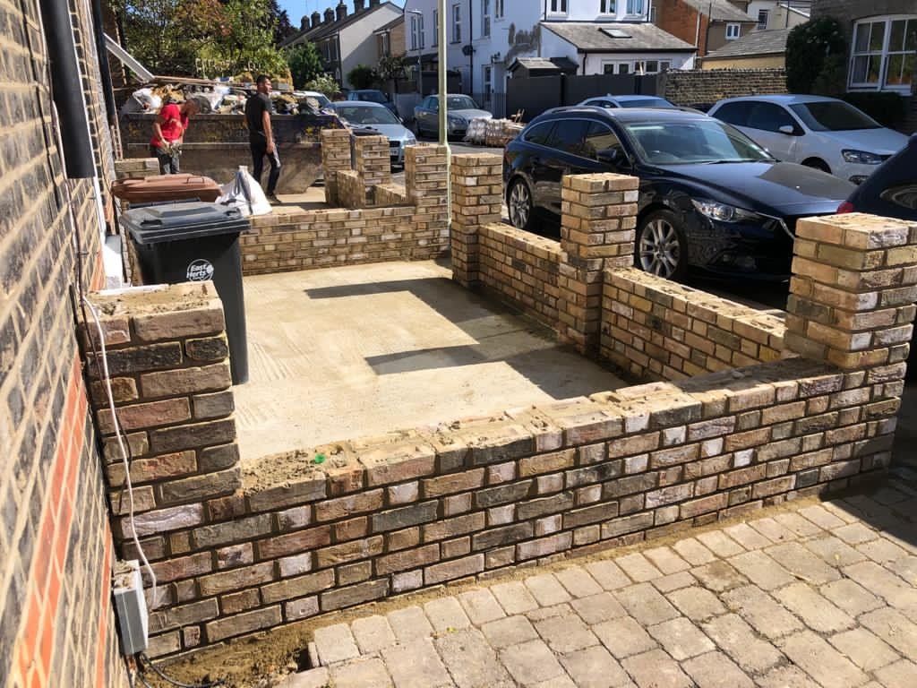 A brick wall with cars parked in front of it.
