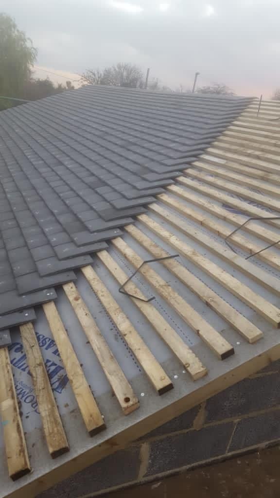 A roof is being built with wooden beams and shingles.