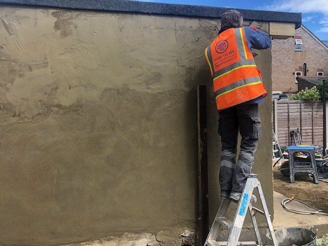 A man is standing on a ladder painting a wall.