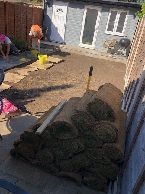 A bunch of rolls of grass are sitting in front of a house
