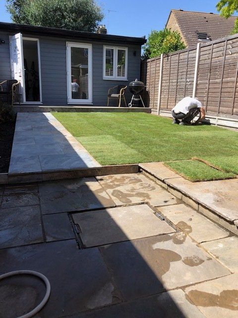 A man is working on a lawn in a backyard
