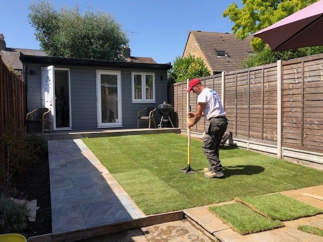 A man is working on a lawn in a backyard.
