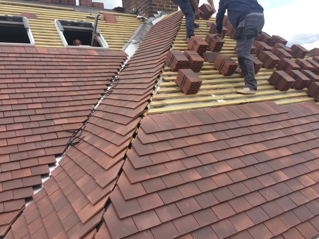 A man is laying bricks on top of a roof.