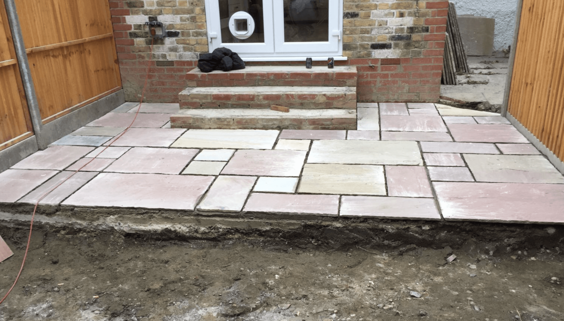 A patio is being built in front of a brick house.