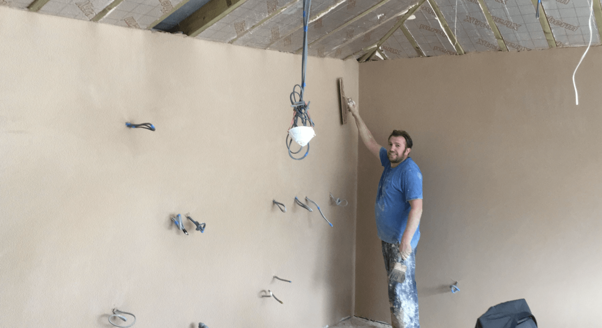 A man is standing in a room holding a trowel.