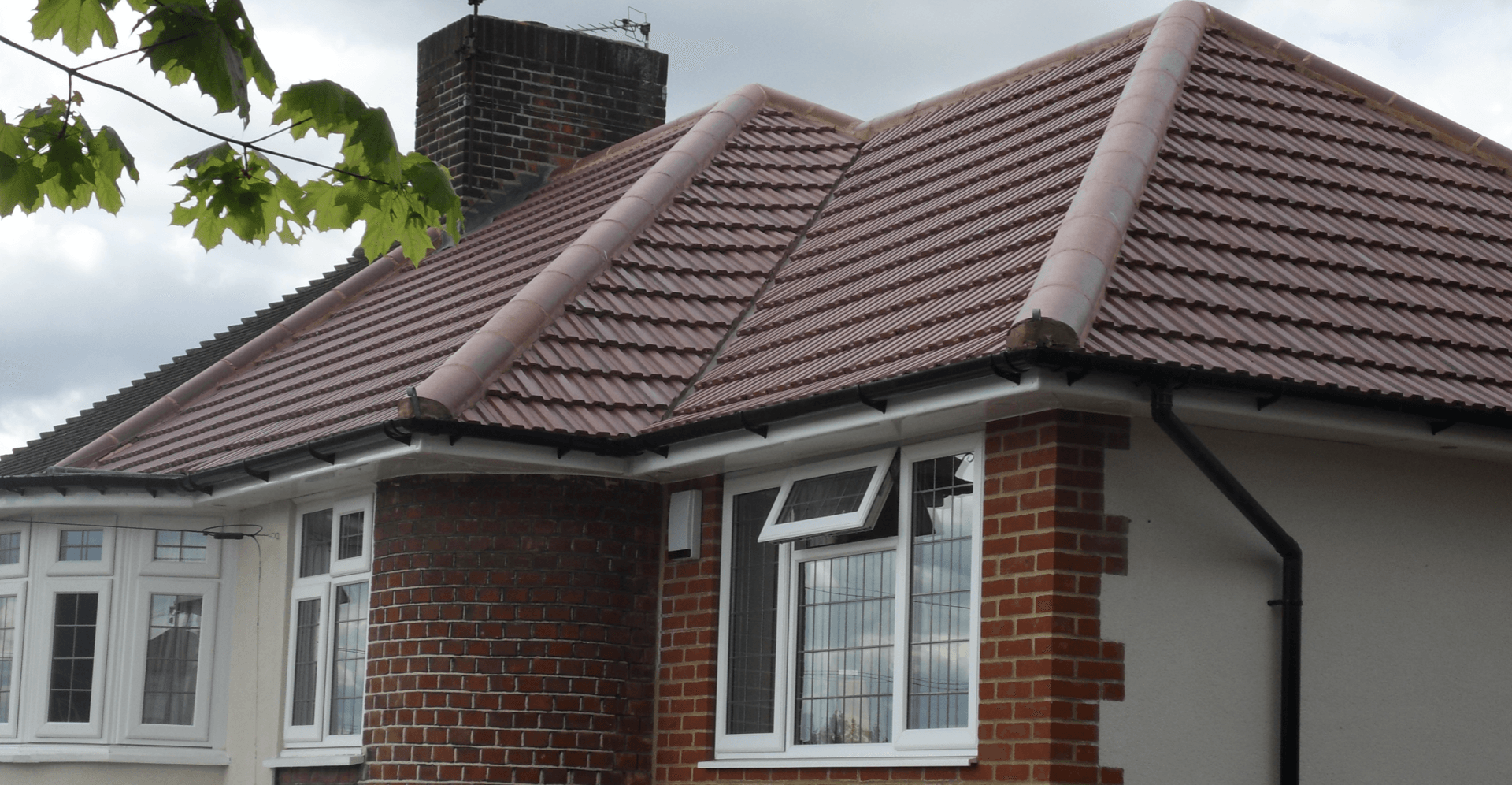 A brick house with a tiled roof and white windows