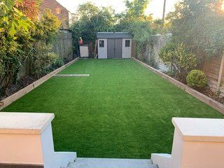 There is a shed in the backyard with a lot of grass.