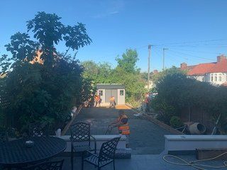 A group of people are working on a driveway in a backyard.