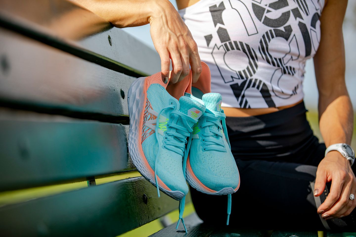 A woman is sitting on a bench tying her shoes.