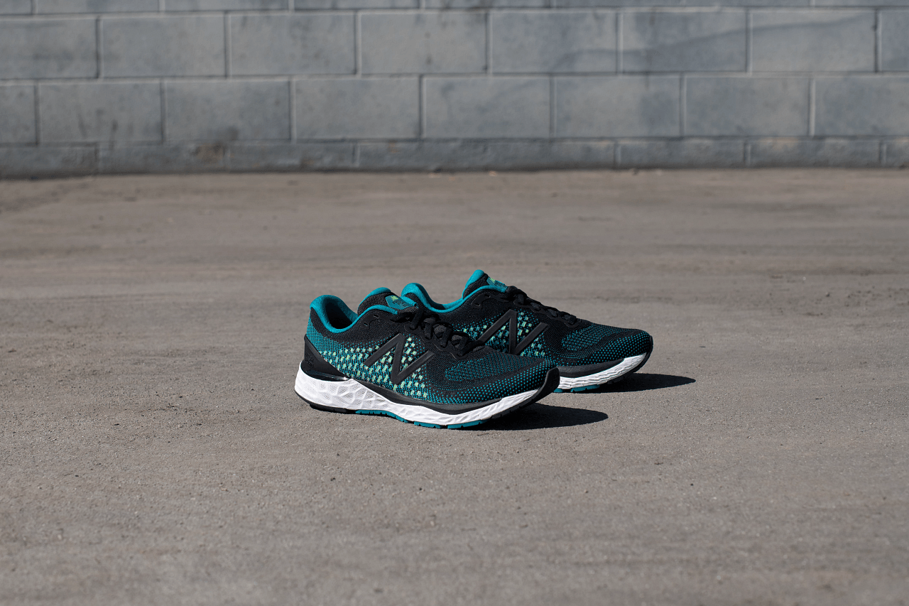 A pair of running shoes are sitting on the ground in front of a brick wall.