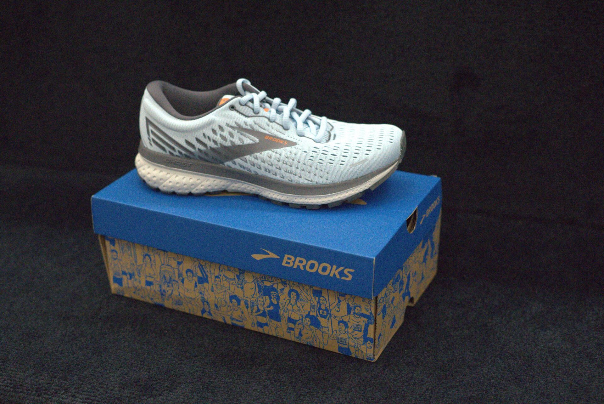 A pair of brooks running shoes is sitting on top of a blue box.