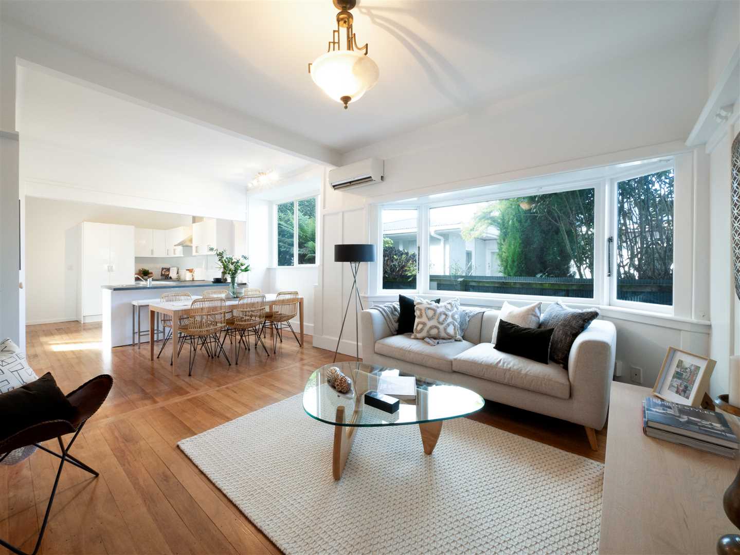 A living room with a white couch and a glass coffee table.