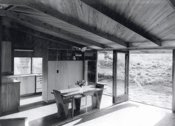 A black and white photo of a house with a table and chairs