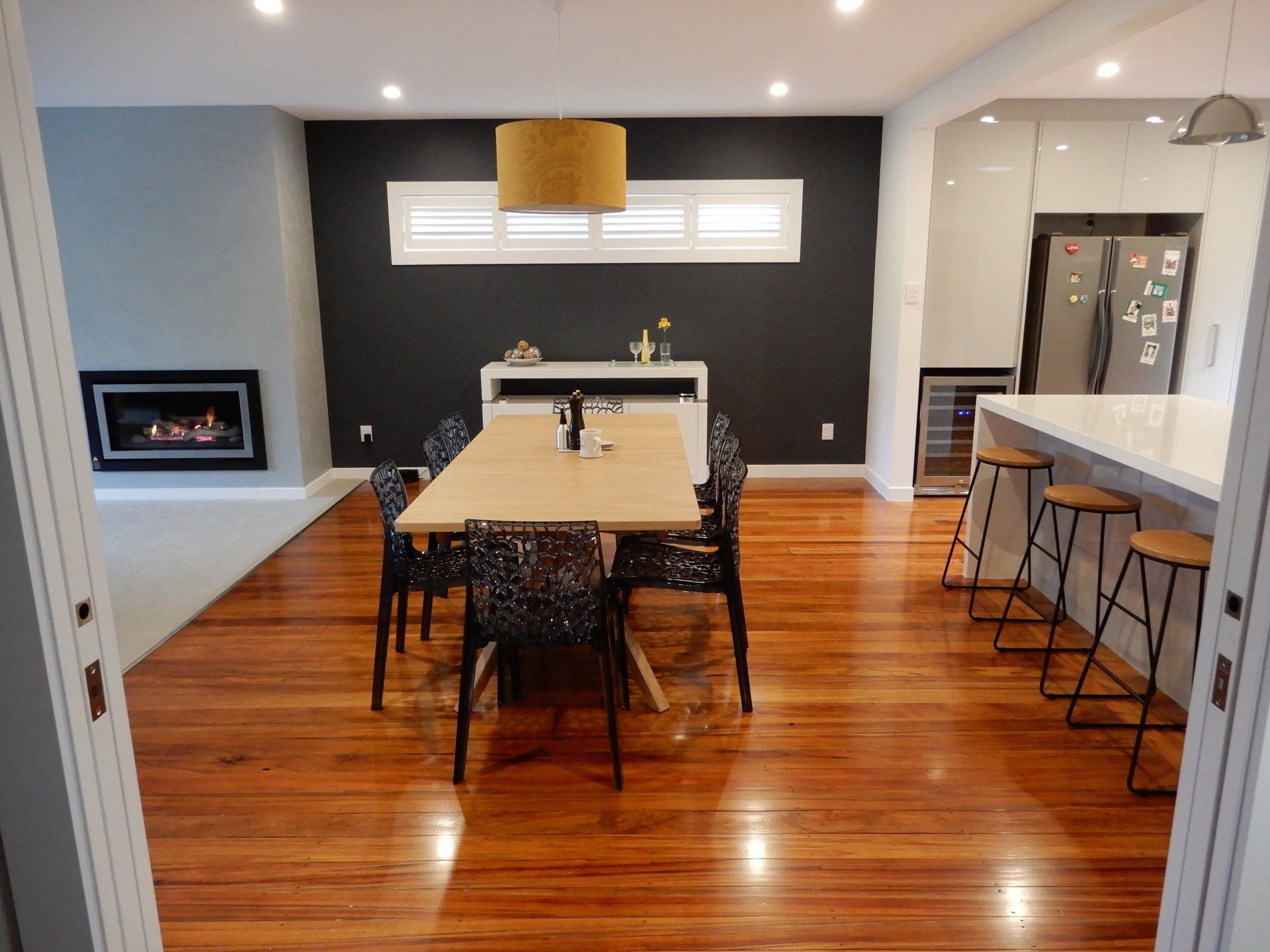 A dining room with a wooden table and chairs and a fireplace.