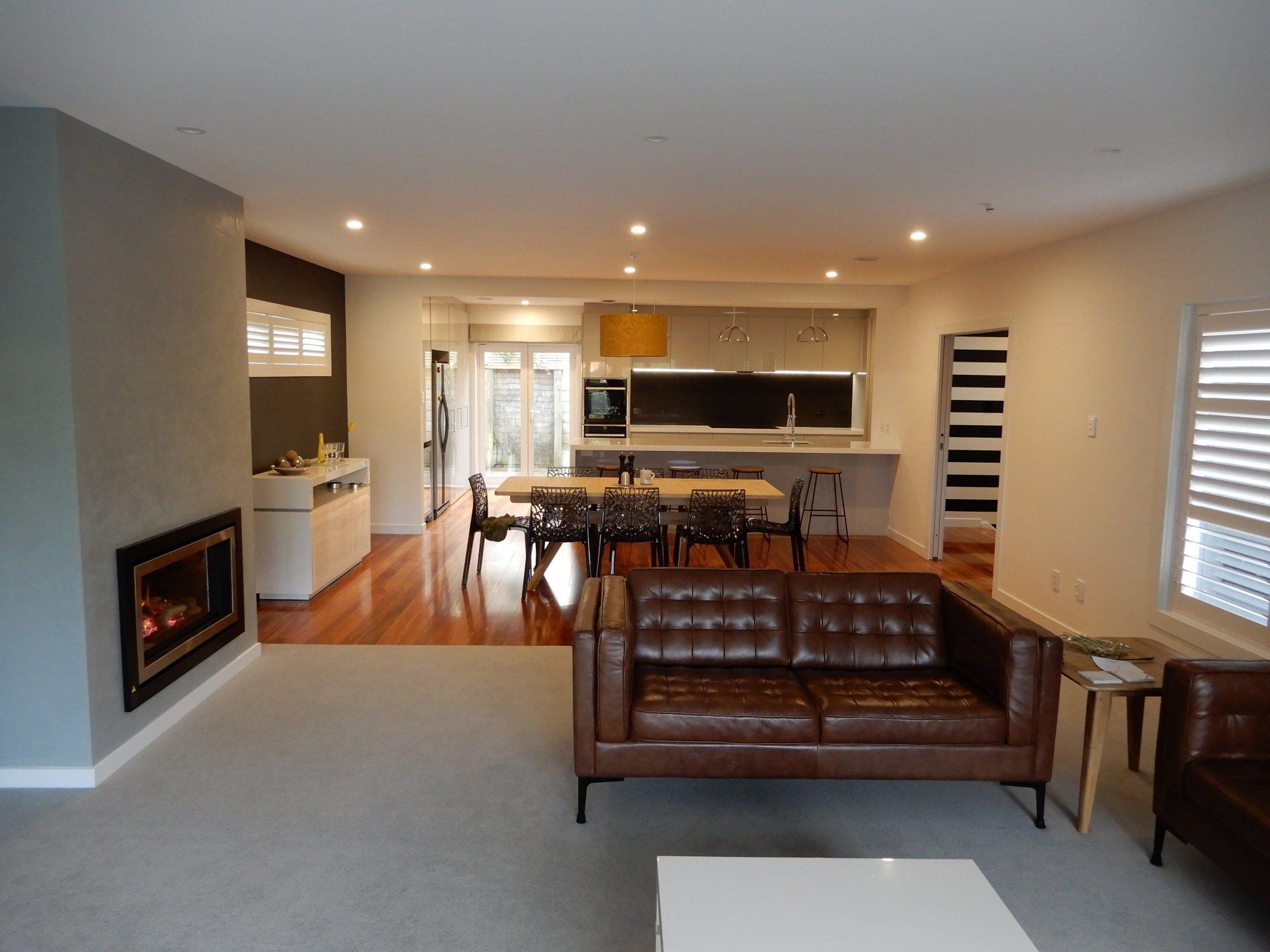 A living room with a brown leather couch and a fireplace
