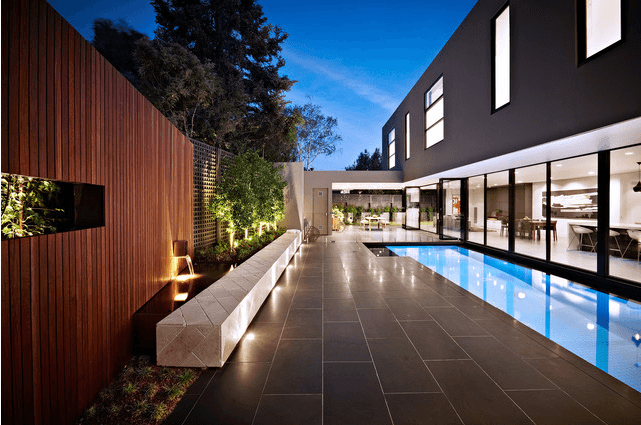 There is a large swimming pool in the backyard of a house.