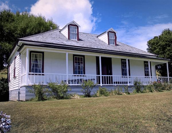 A white house with a porch and a gray roof