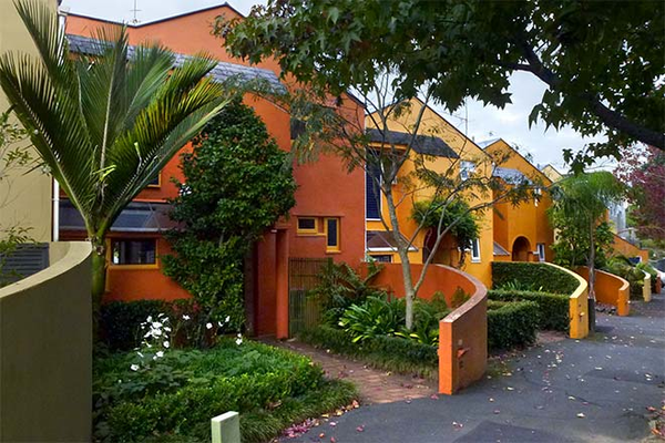 A row of orange and yellow houses with trees in front of them