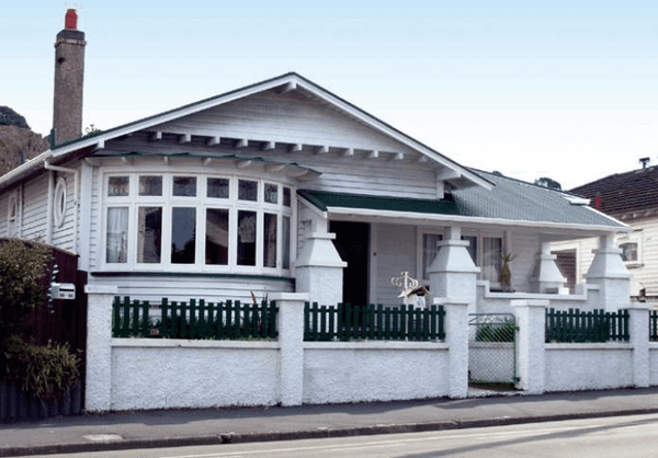 A white house with a green roof and a white fence