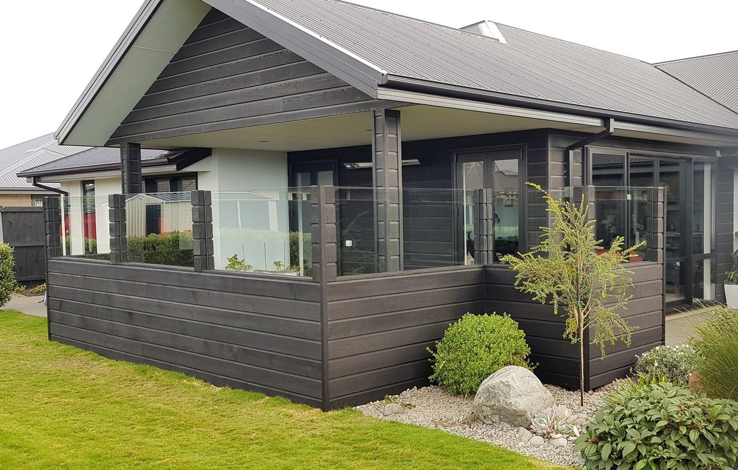 A black house with a glass fence in front of it.