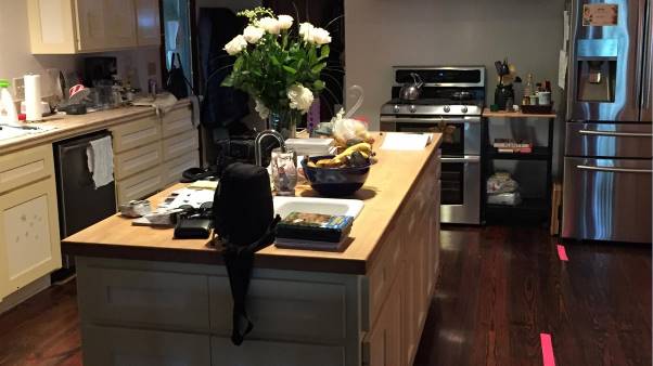 A kitchen with a large island and a stainless steel refrigerator