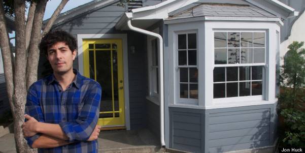 A man standing in front of a house with his arms crossed