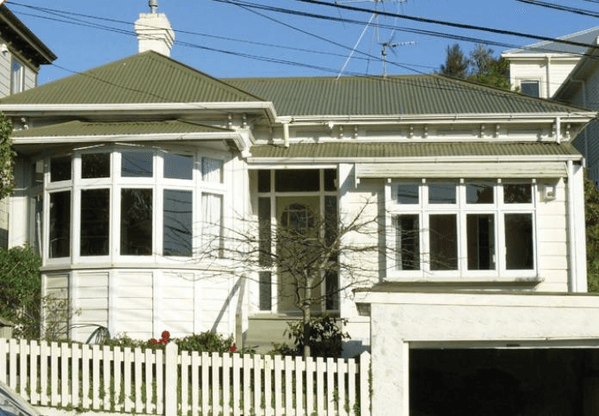 A white house with a green roof and a white picket fence