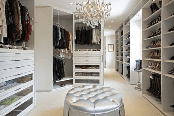 A walk in closet filled with lots of clothes and shoes.