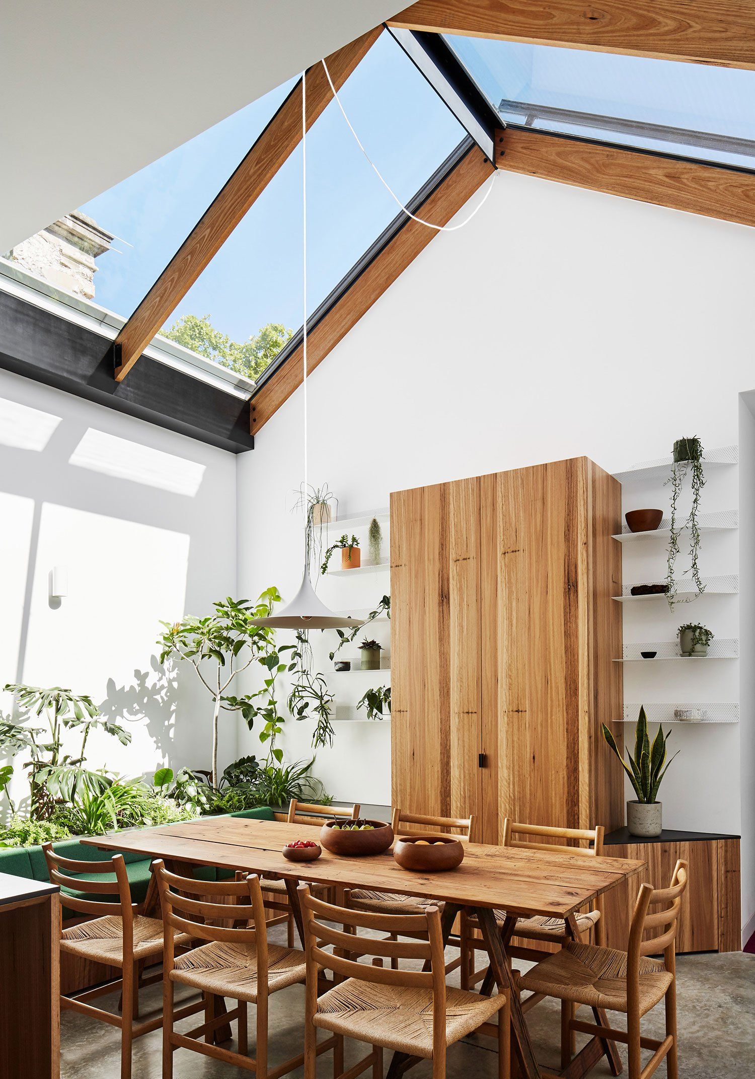 A dining room with a table and chairs and a skylight.
