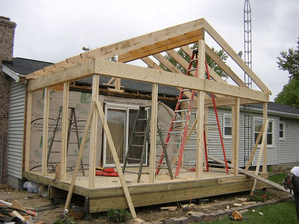 A wooden structure is being built on top of a house