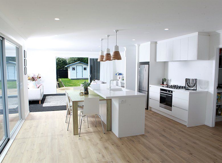 A kitchen with white cabinets , stainless steel appliances , a table and chairs.