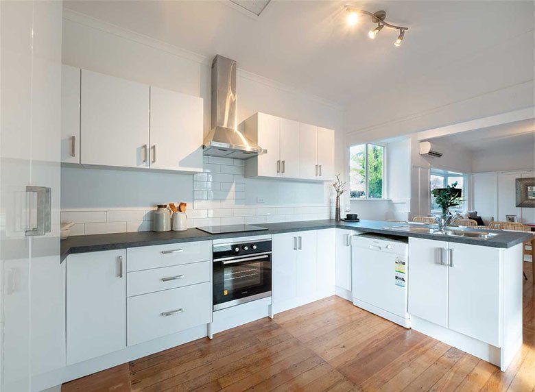 A kitchen with white cabinets and wooden floors